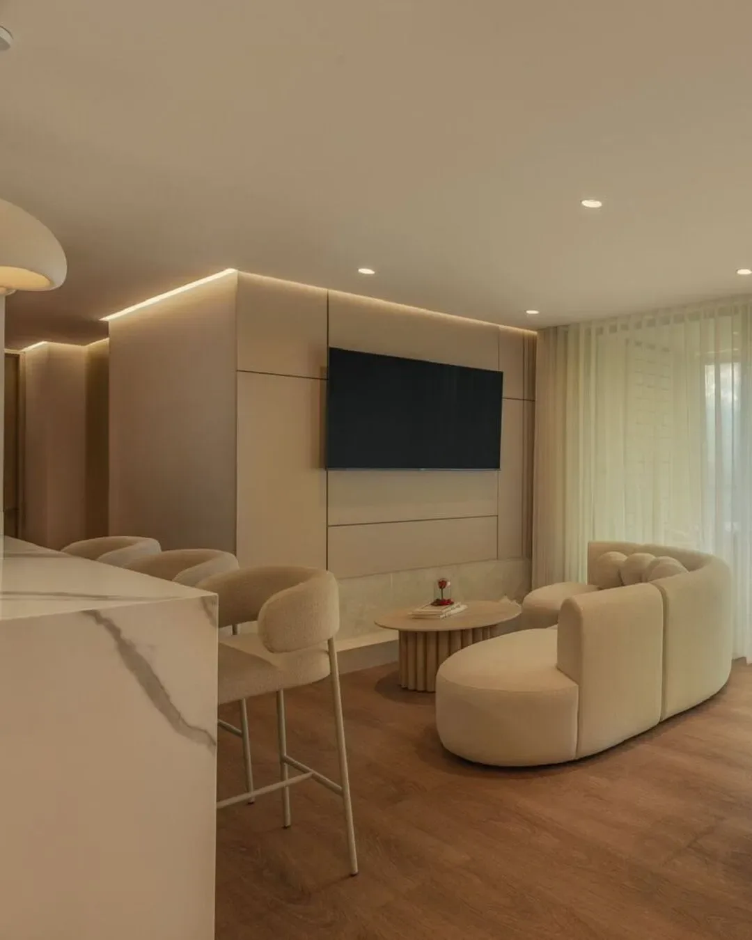 Sofá curvo y acabados minimalistas en un ambiente elegante, cálido y atemporal.Sofá curvo y acabados