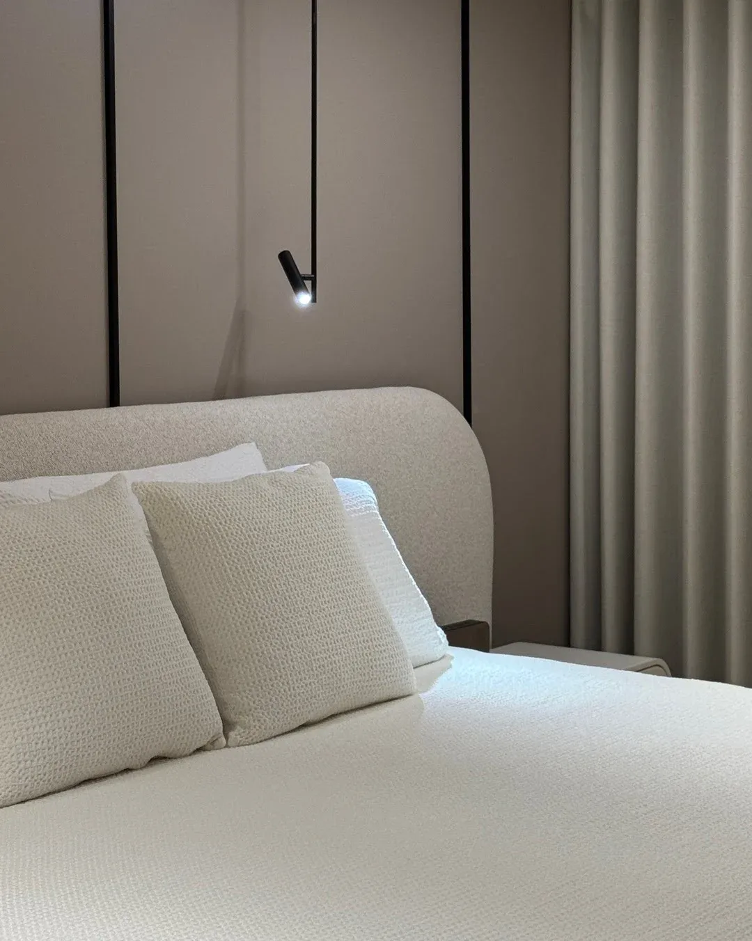 Detalle del tejido texturizado del cabecero curvo de la cama y elementos decorativos.