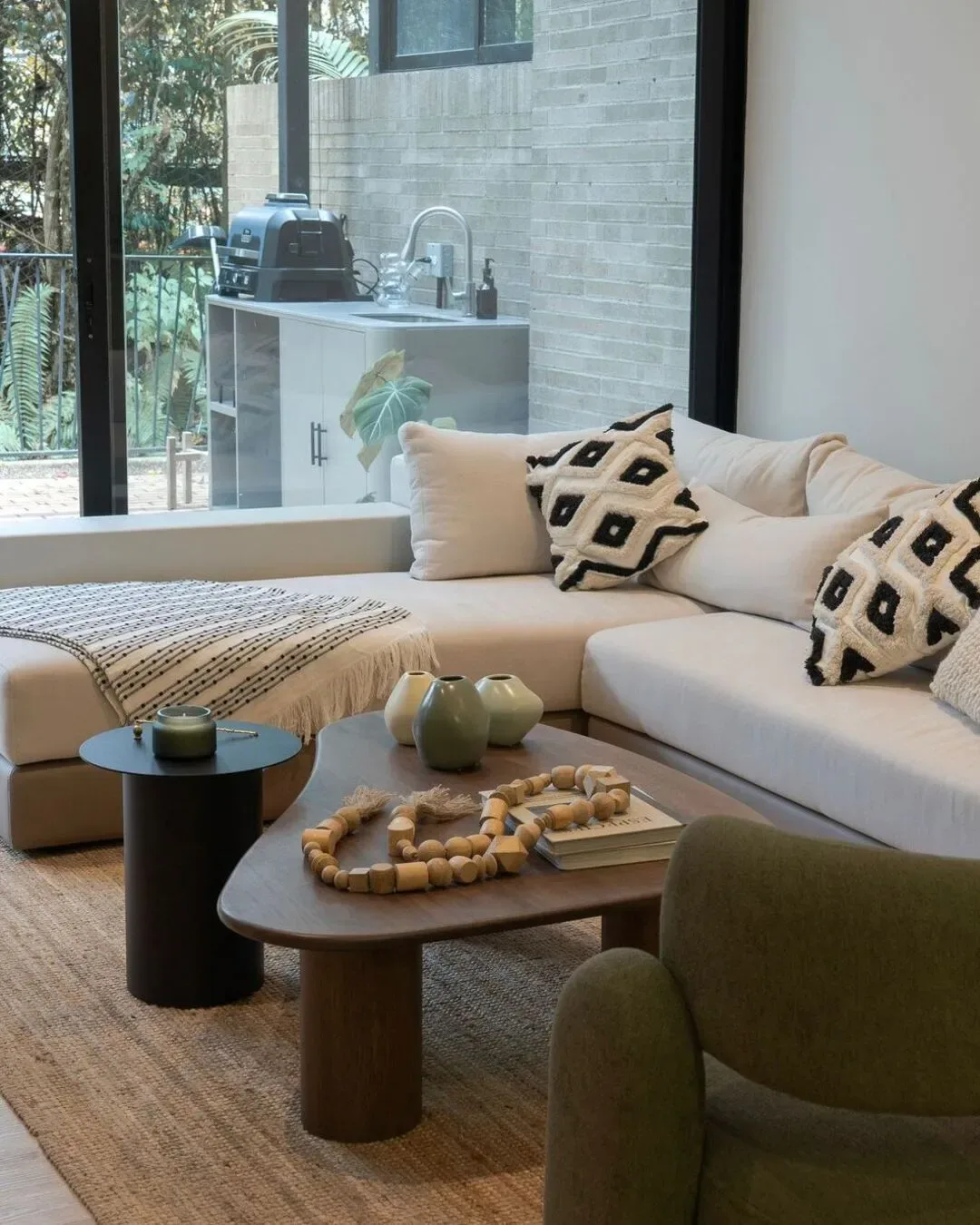 Sofá minimal, modular en textil crema con cojinería geométrica y mesa de centro en madera.