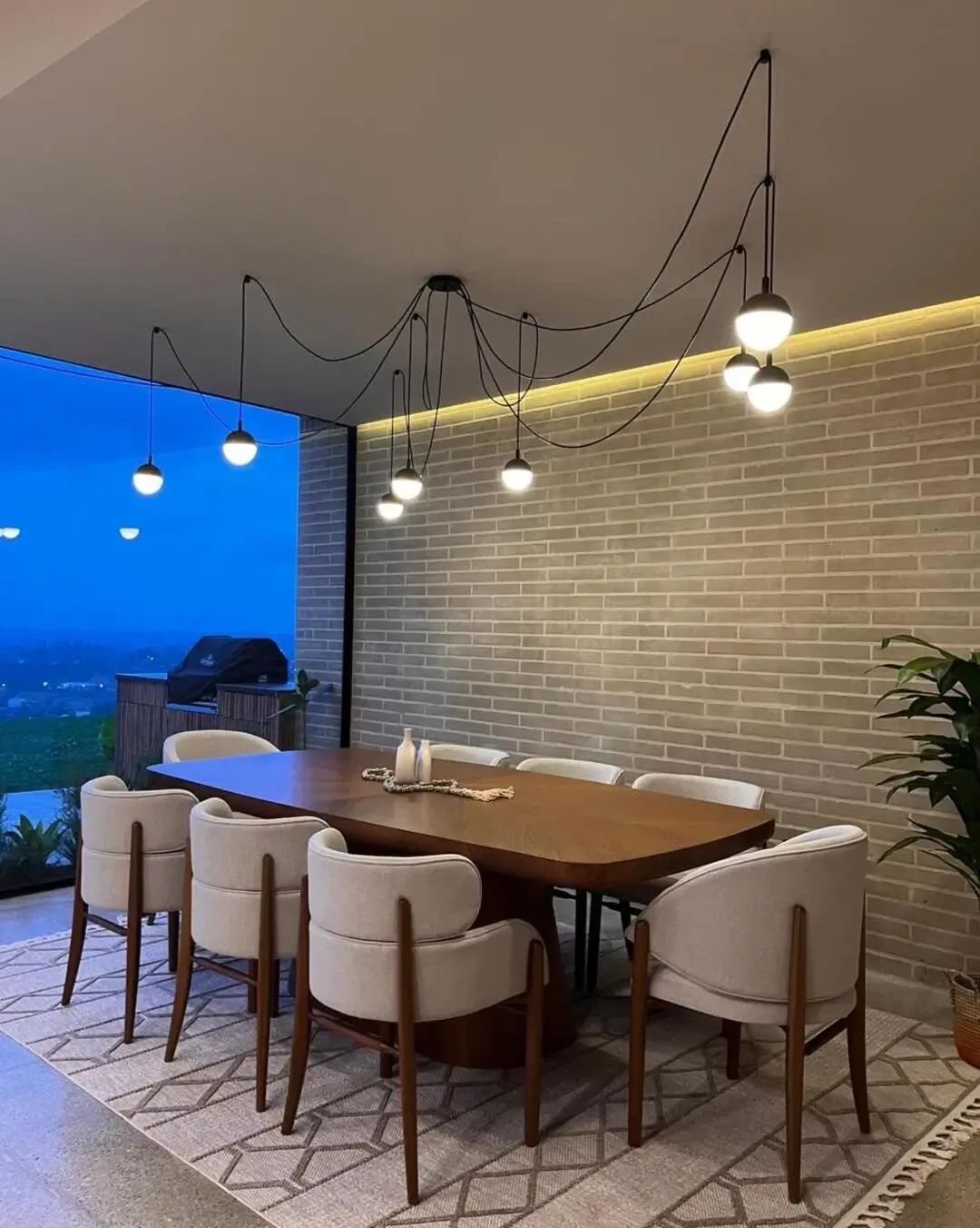Comedor rústico industrial con sillas tapizadas, madera natural y lámparas suspendidas.