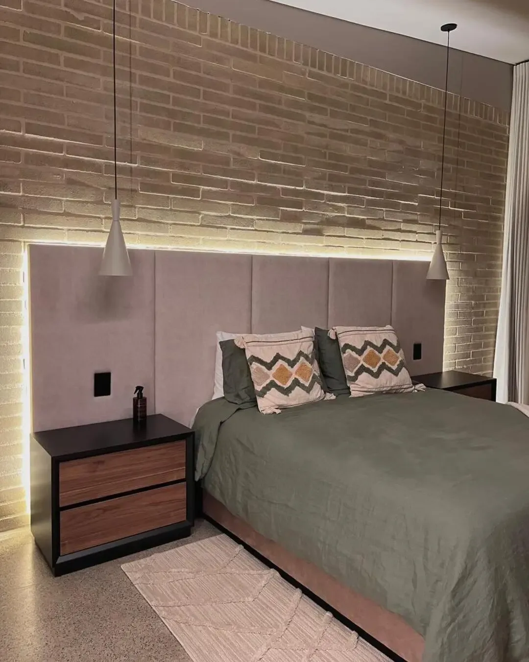 Dormitorio rústico industrial con cabecero tapizado, iluminación lineal y mobiliario funcional.