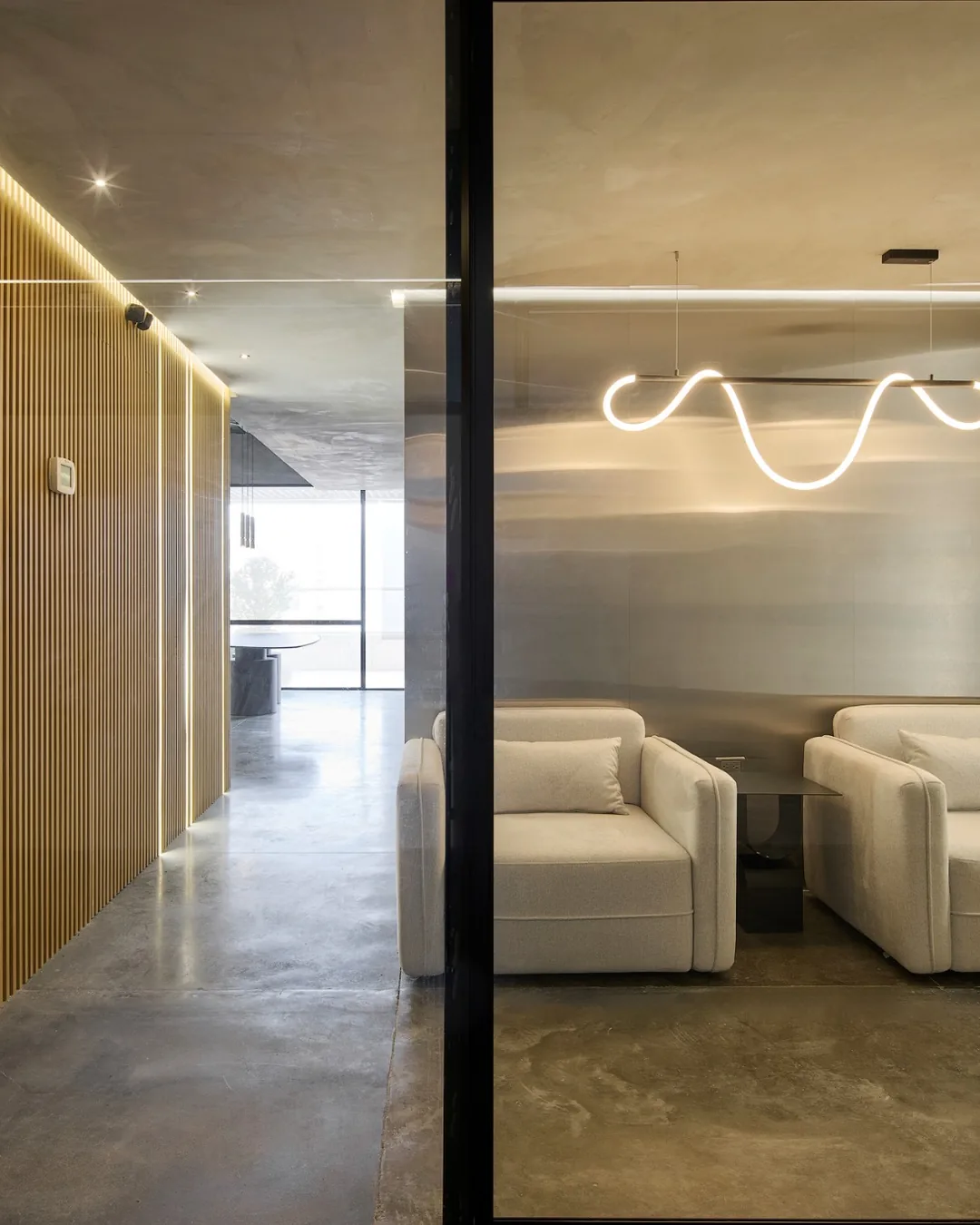 Espacio interior moderno visto a través de puerta de vidrio con mobiliario personalizado y diseño ar