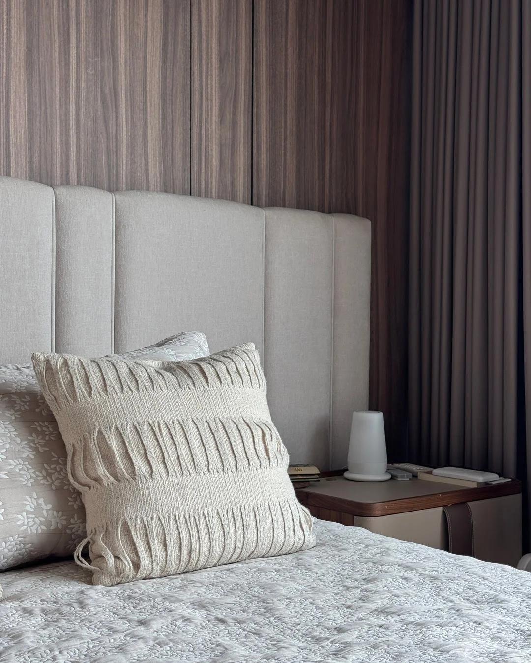 Detalle de un cojín de punto grueso sobre una cama moderna, resaltando la suavidad y el diseño.