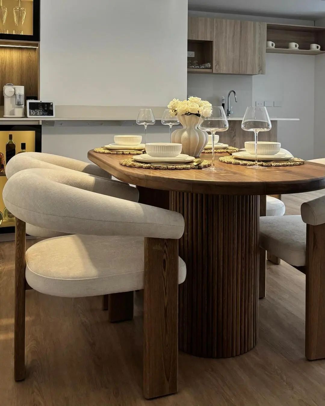 Primer plano de una mesa de comedor de madera ovalada con puestos servidos y flores blancas como cen