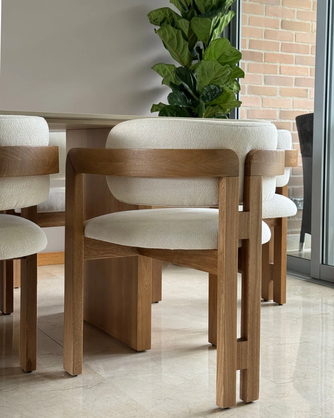 Silla de comedor tapizada en tela bouclé blanca con estructura de madera, diseño elegante.